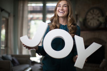 A woman holding a sign of the word Joy