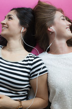 women lying on the floor listening to earbuds 