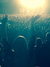 a woman standing with hands raised in the air at a concert 