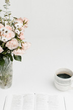 open Bible, coffee cup, and vase of flowers 