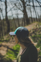 a woman standing outdoors wearing a ball cap 