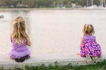 Girls sitting by a lake. 