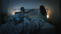 Man playing guitar on a bed at night