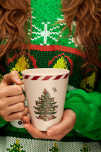 a woman in a Christmas sweater t-shirt holding a mug 