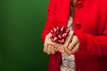 a woman in a red peacoat holding a gift box 