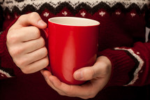 a man in a sweater holding a mug 