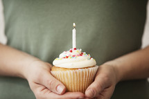 hands holding a birthday cupcake 