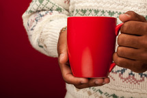 holding a red mug wearing a sweater 