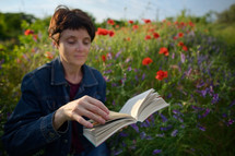 a woman reading a book in a field of wildflowers 