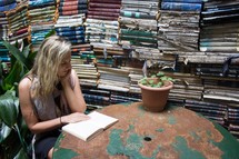 woman reading in front of stacks of old books 
