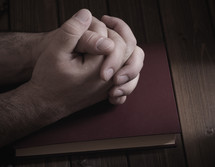 praying hands on a Bible