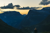 a woman looking out at mountains at sunset 