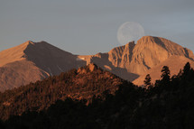 Harvest moon over a mountain peak 