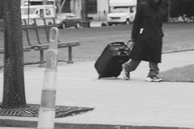 A homeless man dragging a suitcase 