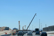 construction cranes over a freeway under construction