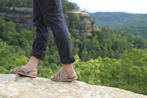 a woman in sandals walking on a rock 