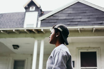 African American youth in a backward ball cap standing in front of a house 