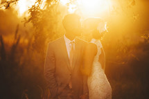 bride and groom kissing outdoors under the glow of sunlight