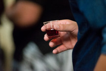 person holding a communion wine cup 