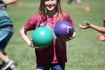 a little girl holding dodge balls 