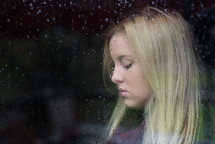 side profile of a woman through a rainy window 