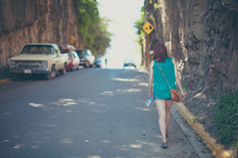 a woman walking down a street holding a water bottle 