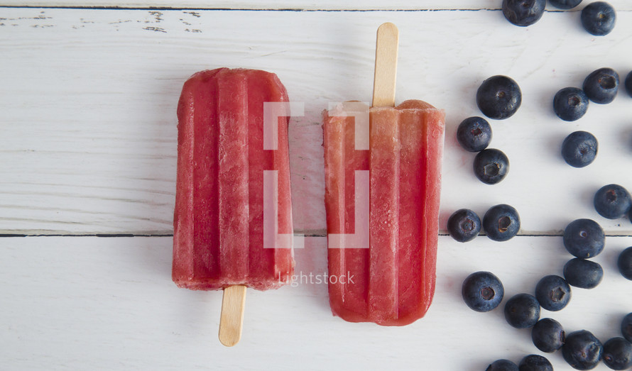 Frozen Homeamde Blueberry Popsicles on a White Wood Table
