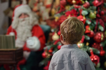 A Boy with Cochlear Implants standing in front of Santa 