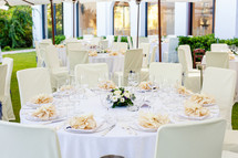 White lace tablecloth on large round tables set for a wedding