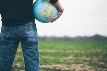 man standing in a field holding a globe
