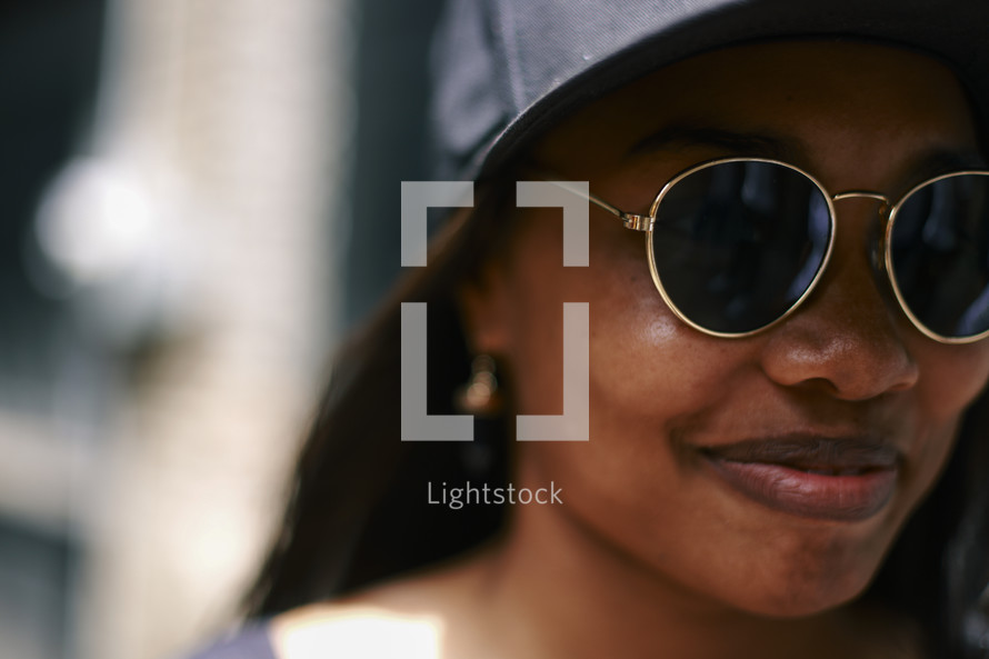 African American woman in sunglasses and ball cap 