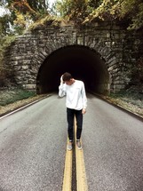 man standing in the middle of a road in front of a tunnel 