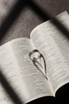 Wedding band in the pages of a Bible forming a heart shadow 