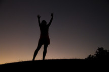 silhouette of a woman with raised hands at night 