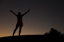 silhouette of a woman with raised arms at night 