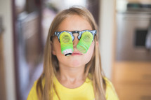 Young girl wearing toy glasses with dangling google eyes.