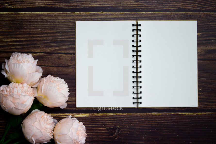 Blank notebook on wooden table with flowers