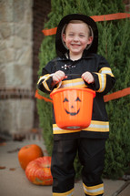 a boy child in a fire fighter costume trick-or-treating 