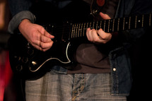 torso of a man playing an electric guitar 
