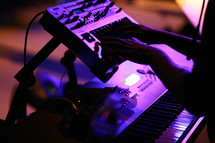 hands playing a keyboard at a concert