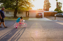 a father watching his daughter ride a bicycle 
