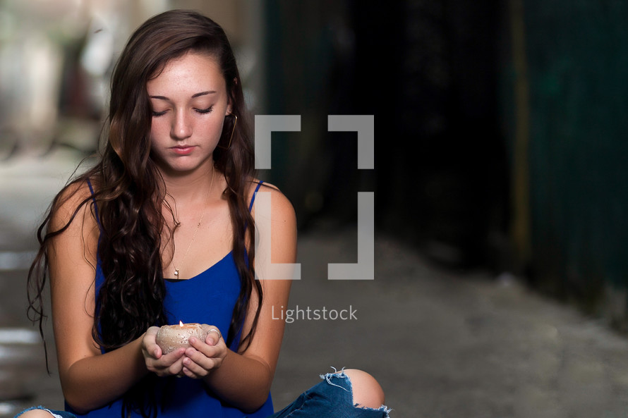 teen girl sitting holding a candle 