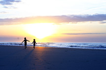 silhouettes of children running on a beach 