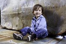 boy sitting on stone floor against rock 