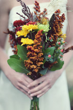 Woman's hands holding bouquet of wildflowers.