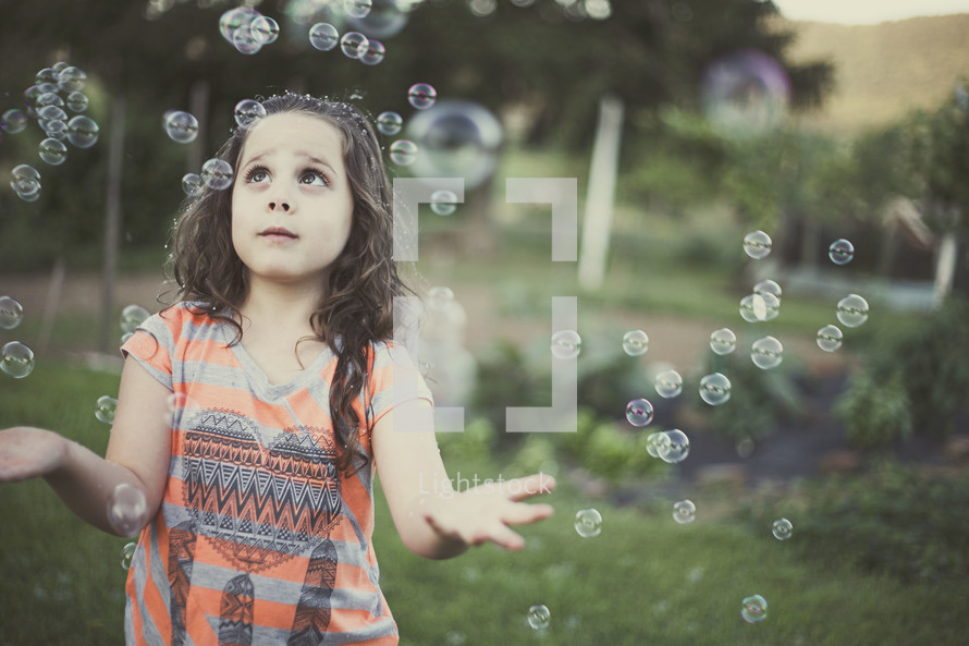A little girl playing in bubbles