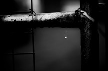 water drop falling off a metal fence