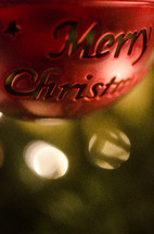 Red metal ball Merry Christmas ornament hanging on Christmas tree.