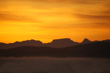 sunset or sunrise over misty mountain range