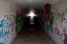 A long tunnel covered in graffiti.
